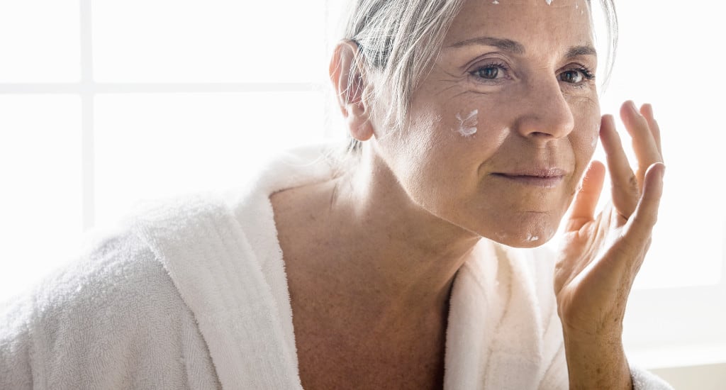 Ältere Frau pflegt ihr Gesicht mit Naturkosmetik