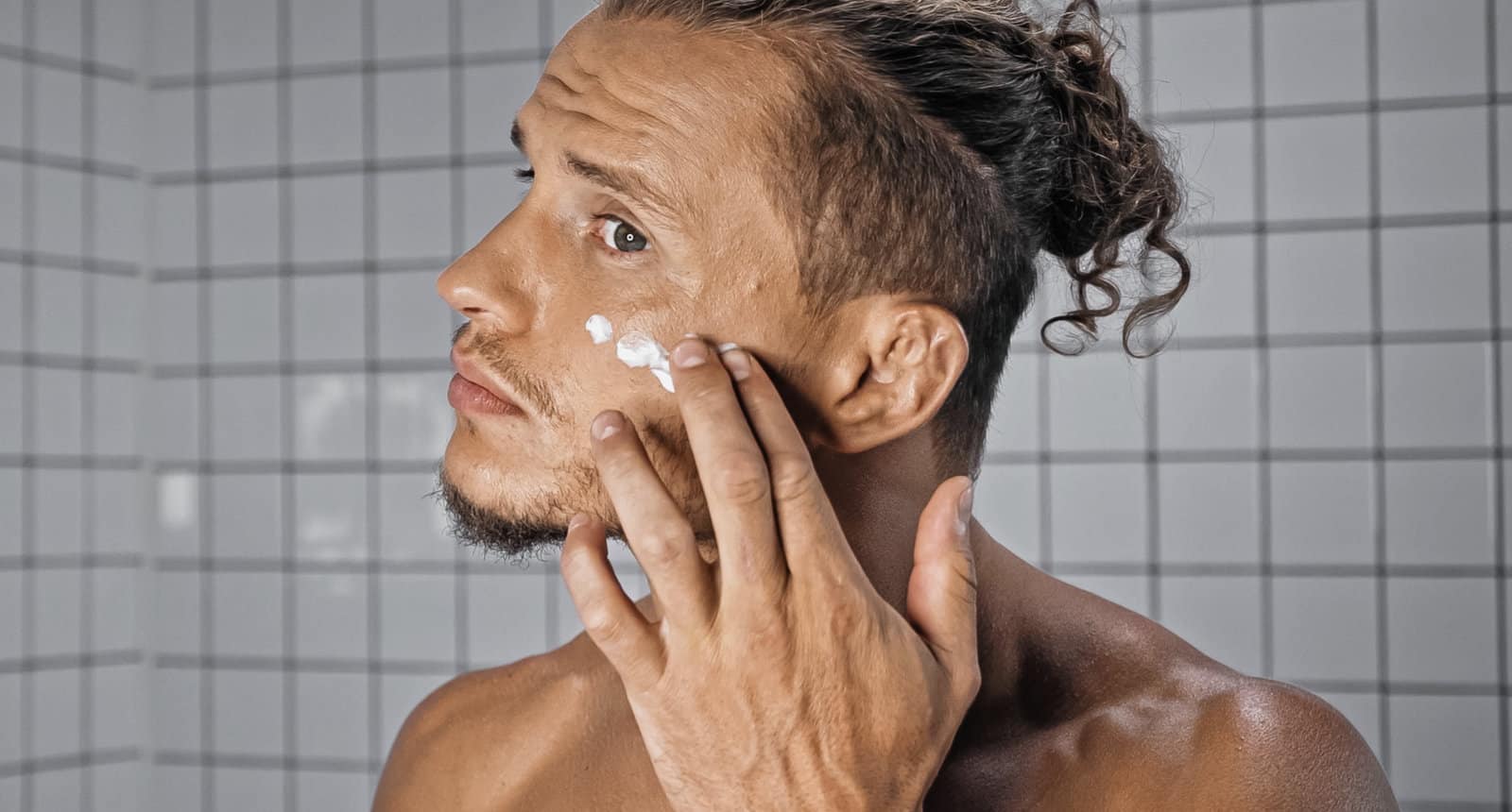 Mann mit empflindlicher Haut cremt sein Gesicht ein